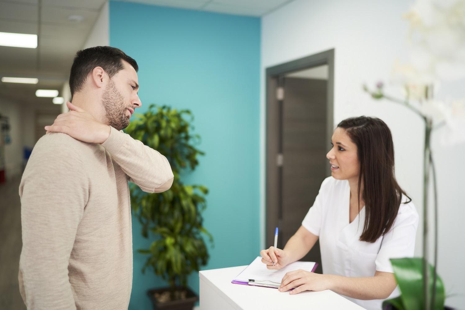 physiotherapist and patient at the clinic’s reception desk Patient talking to physiotherapy receptionist