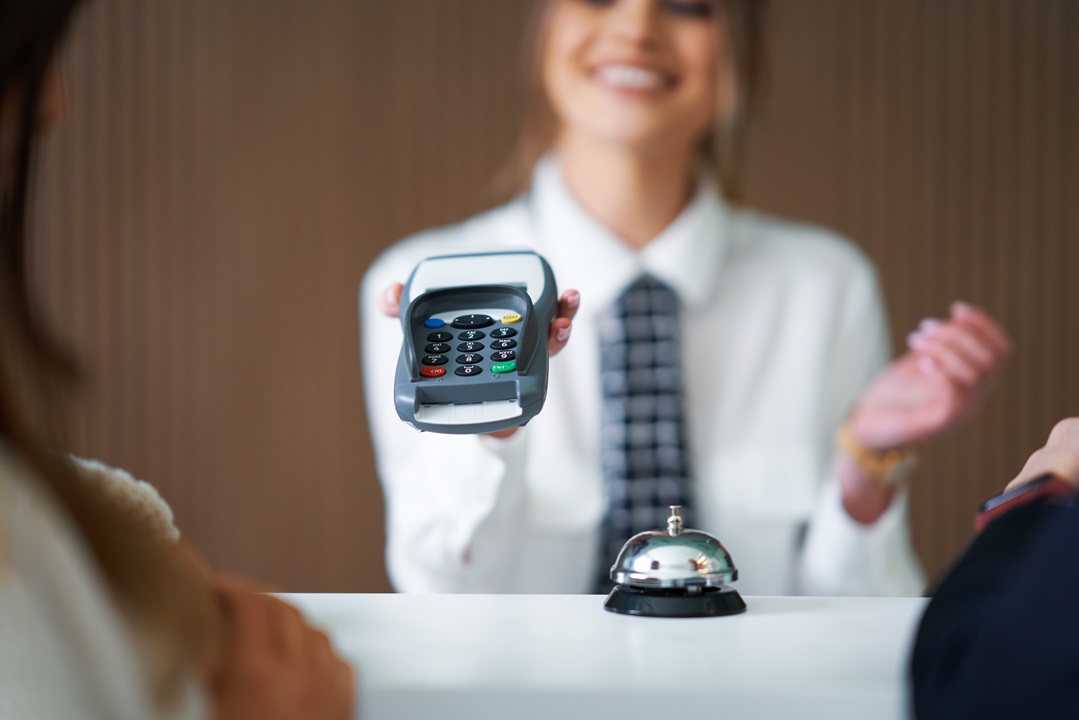 Receptionist waiting for payment in a hotel Receptionist helping decreasing cost-to-collect revenue cycle healthcare